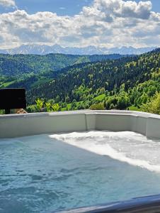 uma banheira de hidromassagem com vista para as montanhas em Bacówki Resort em Ochotnica Górna