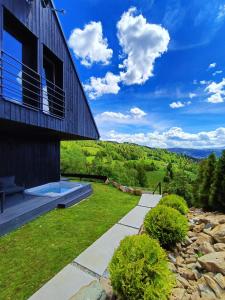 uma casa numa colina com vista para um jardim em Bacówki Resort em Ochotnica Górna