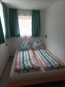 2 łóżka w małym pokoju z zielonymi zasłonami w obiekcie Ferienwohnung Innergreit w Alpbach
