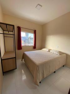 a bedroom with a bed and a window at Condomínio Farol das Dunas in Santo Amaro