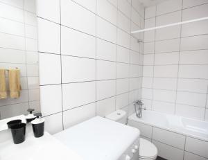 een wit betegelde badkamer met een toilet en een ligbad bij Casa da Viola - Faro in Faro +18 foto's