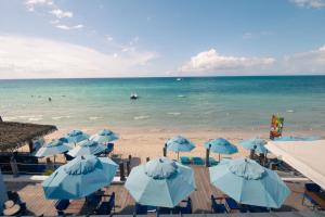 una playa con sombrillas azules y el océano en Blue Skies Beach Resort en Negril