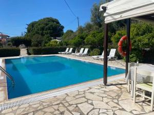 a swimming pool in a villa with an umbrella at Moulinos Studios in Svoronata