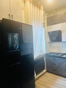 La cuisine est équipée d'un réfrigérateur noir et d'un four micro-ondes. dans l'établissement Apartment in Tashkent City Center, à Yakkasaray