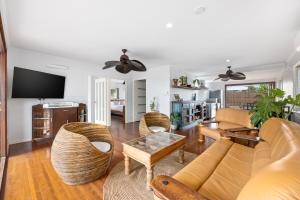uma sala de estar com um sofá e cadeiras e uma televisão em Vila Paus Dua - Beachfront Hervey Bay em Hervey Bay