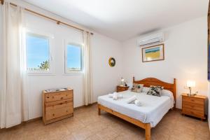 a bedroom with a bed and two windows at Casa Es Vedrà in Cala Saona