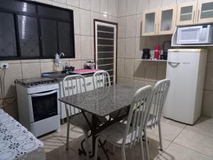 Casa 11 hóspedes Temporada em Ribeirão في ريبيراو بريتو: مطبخ مع طاولة وكراسي وموقد وثلاجة