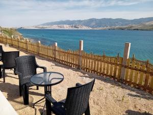 eine Terrasse mit Stühlen, einem Tisch und Wasser in der Unterkunft Hotel Biser in Pag