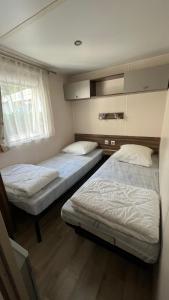 a bedroom with two beds and a window at Mobilhome climatisé, 6 personnes camping les embruns in Lège-Cap-Ferret