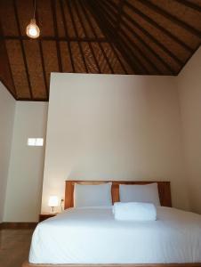 een slaapkamer met een groot wit bed met 2 kussens bij Jepun Homestay Lemukih in Singaraja