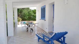 une terrasse avec une chaise bleue et une table dans l'établissement 2 bedrooms house at Marsala 250 m away from the beach with sea view and furnished garden, à Trapani
