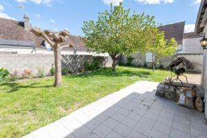 une cour avec un arbre et une maison dans l'établissement L'Intriguante - Maison avec jardin pour 6pers., à Bléré