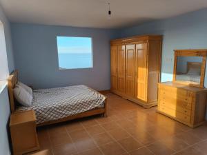 a bedroom with a bed and a wooden cabinet at Villa en el campo sobre el mar in Ras El Ma