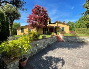 a house with a stone retaining wall and a driveway at Villa Elisa in Scarperia