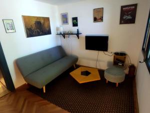 uma sala de estar com um sofá azul e uma televisão em Bocke Beach House em Novi Sad