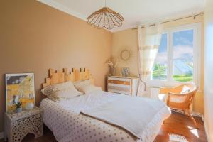 Schlafzimmer mit einem Bett, einem Fenster und einem Kronleuchter in der Unterkunft Maison de vacances proche mer in Plouha