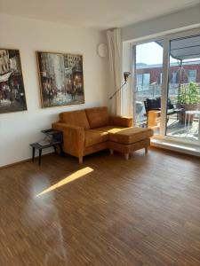 a living room with a brown couch and a window at Penthouse-Wohnung mit Flussblick in Oldenburg +35 photos