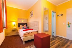 um quarto com paredes amarelas e uma cama e um banco vermelho em Hotel & Restaurant Hanse Kogge em Ostseebad Koserow
