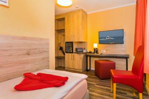 Habitación con cama, escritorio y silla roja. en Hotel & Restaurant Hanse Kogge en Ostseebad Koserow