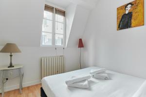 ein weißes Schlafzimmer mit einem Bett und einem Fenster in der Unterkunft Charming 1 bedroom flat Coeur du Marais By Studio Prestige in Paris