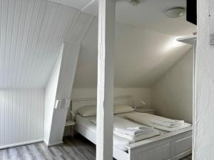 um quarto branco com uma cama num sótão em Hotel Lübecker Hof em Lüneburg