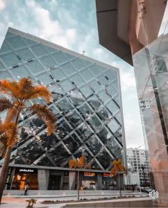 a large glass building with a palm tree in front of it at The Panoramic View - Luxury Apartments in Cairo in Cairo