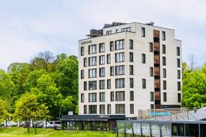 a tall white building with a parking lot at Ilidza River Apartments in Sarajevo