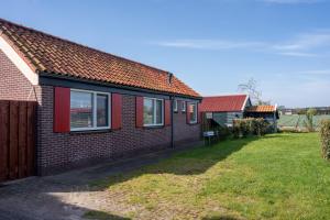 a brick house with red windows and a yard at Het Zomerhuis in Egmond-Binnen