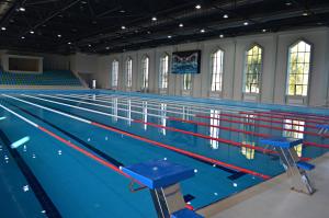 a large swimming pool with blue tables in it at Arena Villas Guba in Quba