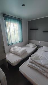 two beds in a room with a window at Mobil home les sables du midi 4 étoiles in Valras-Plage