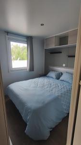 a bedroom with a large white bed with a window at Mobil home les sables du midi 4 étoiles in Valras-Plage