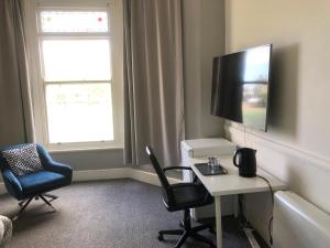 a living room with a tv and a desk and chairs at Green Lodge-Room-04 in Liverpool