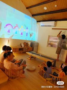 un grupo de niños sentados en sillas frente a una pantalla en 捉鳳凰 台南百年老宅包棟導覽民宿系列Catchphoenix Centennial Guesthouse en Tainan