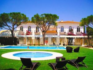 a resort with a pool and chairs and a building at Hotel Albaida Nature in Mazagón