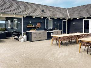 a patio with a kitchen and tables and chairs at 22 person holiday home in Harbo re in Harboør
