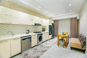 uma cozinha com armários brancos e uma mesa num quarto em Park Azure Luxury apartment by Baku Housing em Baku