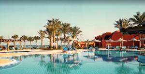 a pool at a resort with palm trees and chairs at Las Cabanas Apartment in Marsa Alam City