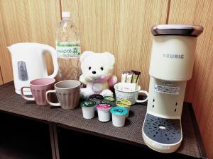 a table with a coffee maker and cups and a teddy bear at SECRET BASE Station Side in Osaka
