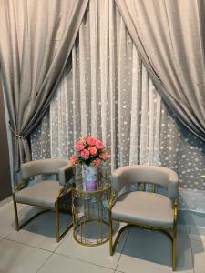dos sillas y una mesa con un jarrón de flores en Alchemy Guesthouse D'summit Residence with Netflix, en Johor Bahru