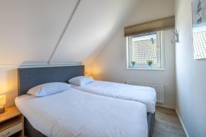 two beds in a small room with a window at Antibes 274 - Kustpark Village Scaldia in Hoofdplaat