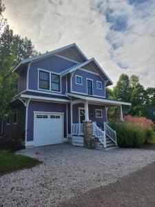 a blue house with a white garage at Blueberry Beach House indoor pool, hot tub in South Haven