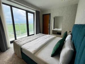 a bedroom with a large bed with a large window at Arena Grand Hotel in Quba