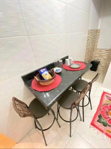 a black table with chairs and a bowl of food on it at Apartamento na Praia in Praia Grande