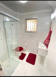 a bathroom with a glass shower and red towels at Apartamento na Praia in Praia Grande