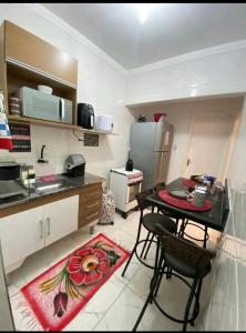 a small kitchen with a table and a refrigerator at Apartamento na Praia in Praia Grande