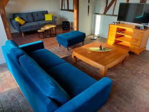a living room with a blue couch and a coffee table at Longère 10 personnes in Vauchelles-lès-Quesnoy