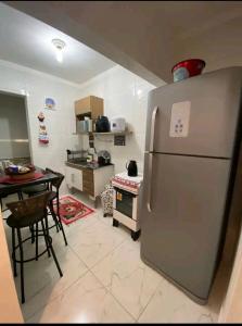 a kitchen with a stainless steel refrigerator and a table at Apartamento na Praia in Praia Grande