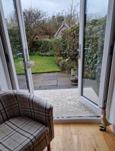 uma porta de vidro deslizante aberta com um sofá na sala de estar em Troon Open golf - Private house with garden in central Prestwick em Prestwick