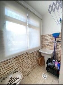 a bathroom with a sink and a window and a toilet at Apartamento na Praia in Praia Grande