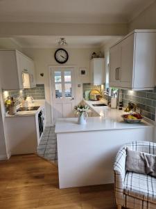 a kitchen with white cabinets and a clock on the wall at Troon Open golf - Private house with garden in central Prestwick in Prestwick